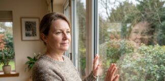 Fenêtre double vitrage : est-ce le bon choix pour vous ? Femme en sweater regardant par une grande fenetre moderne